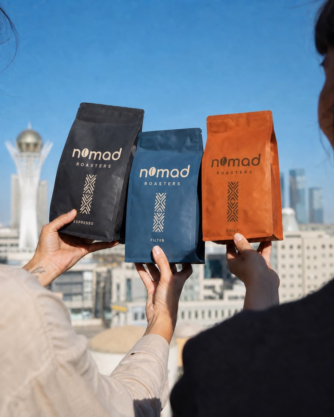 Три фирменные линии кофе Nomad Roasters на фоне Астаны